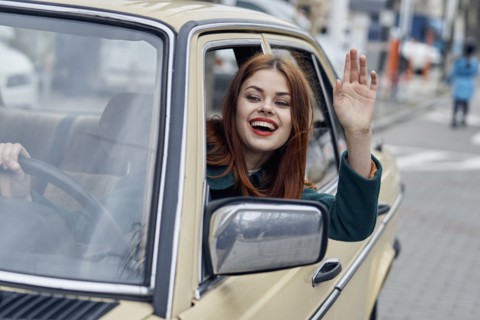 Smiling Caucasian woman driving car and waving