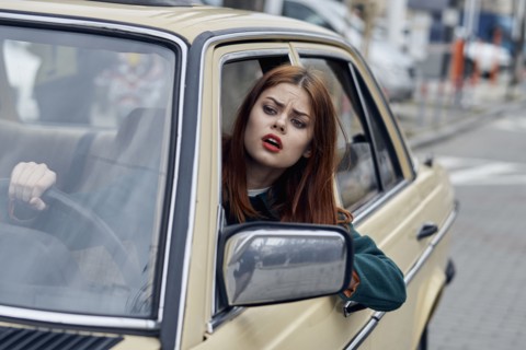 Frustrated Caucasian woman leaning on door driving car