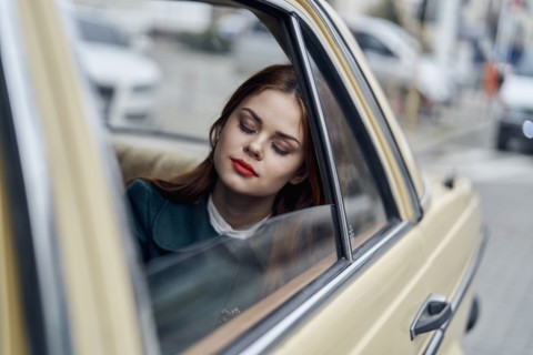 Caucasian woman sleeping in back seat of car