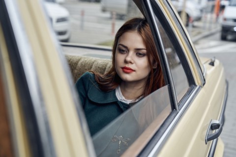 Pensive Caucasian woman in back seat of car