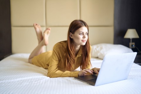 Caucasian woman laying on bed using laptop