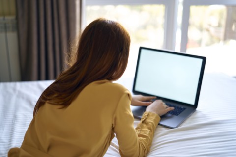 Caucasian woman laying on bed using laptop