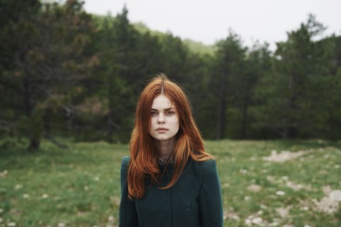 Serious Caucasian woman wearing coat in field