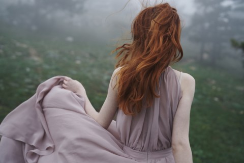 Wind blowing hair of Caucasian woman in field