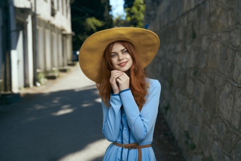 Pensive Caucasian woman wearing hat near stone wall