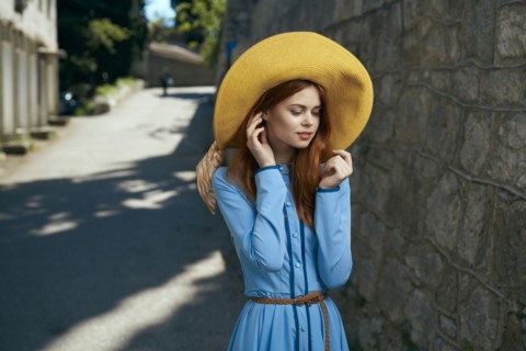 Pensive Caucasian woman wearing hat near stone wall