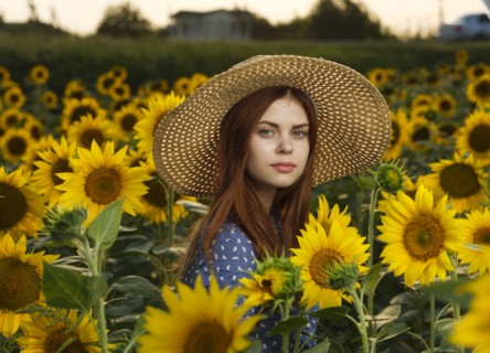 Serious Caucasian woman wearing hat in field of sunflowers
