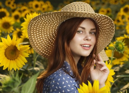 Smiling Caucasian woman wearing hat in field of sunflowers