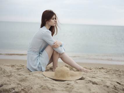 Pensive Caucasian woman sitting on beach