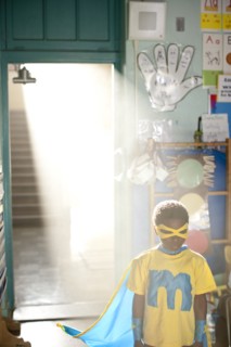 African American boy wearing superhero costume in classroom