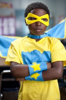African American boy wearing superhero costume in classroom