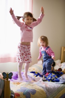 Two girls jumping on bed