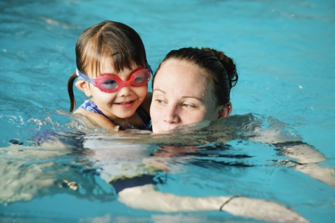 Mother and young daughter swimming