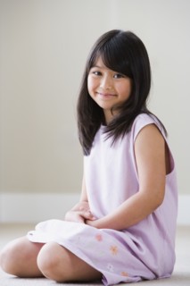 Young Asian girl sitting on floor smiling
