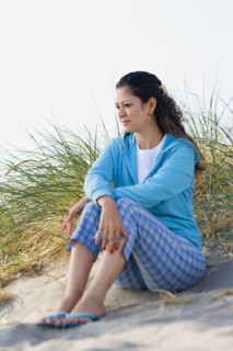 Hispanic woman sitting on beach