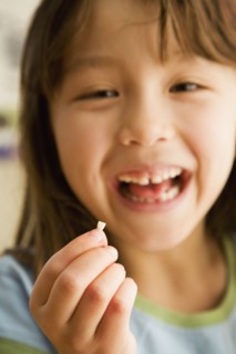 Asian girl smiling and holding tooth