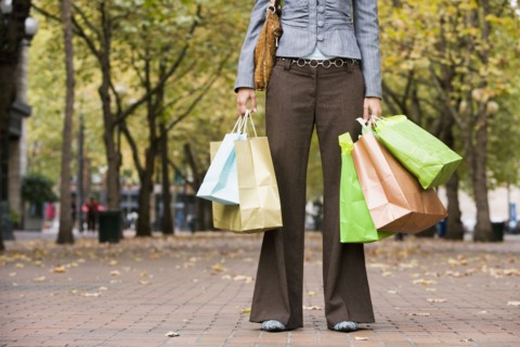 Woman holding shopping bags in urban park