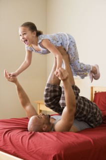 African girl balancing on father's feet