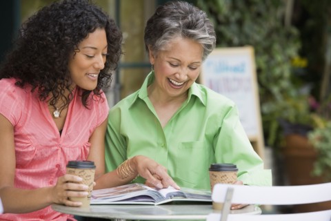 African American mother and adult daughter looking at photo album