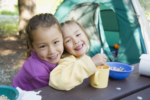 Asian sisters eating at campsite