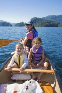 Mother and daughters rowing canoe on lake