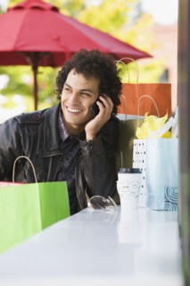Middle Eastern man with shopping bags talking on cell phone