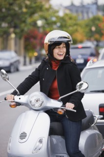 Mixed race woman in helmet driving scooter
