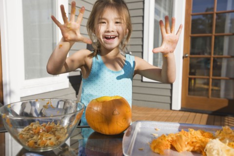 Mixed race young girl preparing Halloween pumpkin