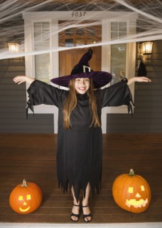 Mixed race young girl in witch costume with Halloween pumpkins
