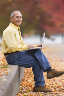 Hispanic man using laptop outdoors in autumn