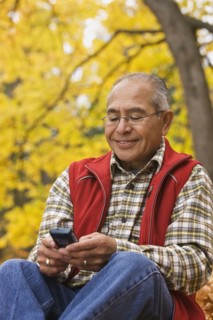 Hispanic man using cell phone outdoors in autumn