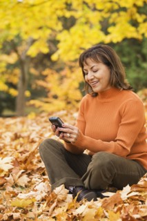 Hispanic woman using cell phone outdoors in autumn
