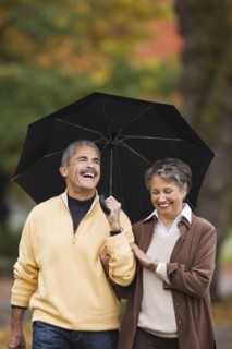 African couple walking with umbrella in autumn