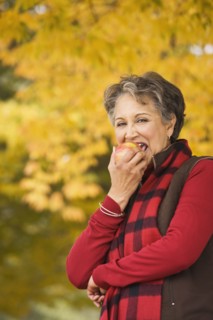 African woman eating apple outdoors in autumn