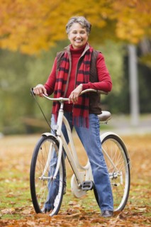 African woman standing with bicycle in park in autumn
