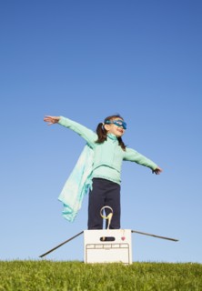Mixed race girl wearing cape and standing in box