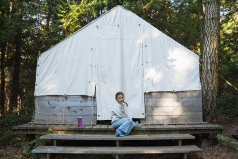 Mixed race girl sitting near tent