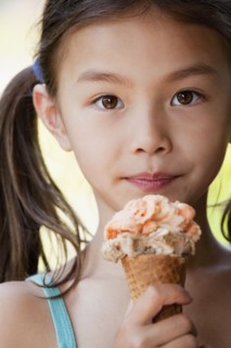 Mixed race girl eating ice cream cone