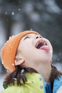 Mixed race girl catching snowflakes on tongue