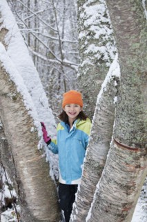 Mixed race girl standing on snowy tree