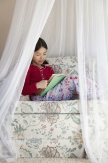 Mixed race girl reading on sofa