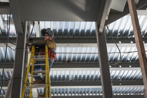 Caucasian construction worker standing on ladder