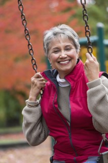 Mixed race woman on swing in park