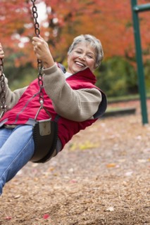 Mixed race woman on swing in park