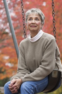 Mixed race woman on swing in park
