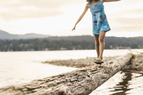 Mixed race girl walking on log