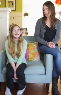 Caucasian mother and daughter smiling in living room