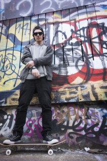 Caucasian teenage boy on skateboard by graffiti wall
