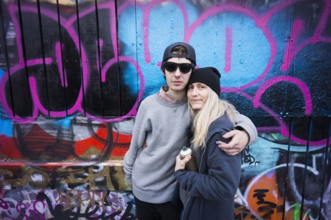 Caucasian mother and son hugging by graffiti wall