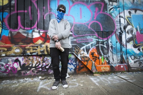 Caucasian teenage boy standing by graffiti wall